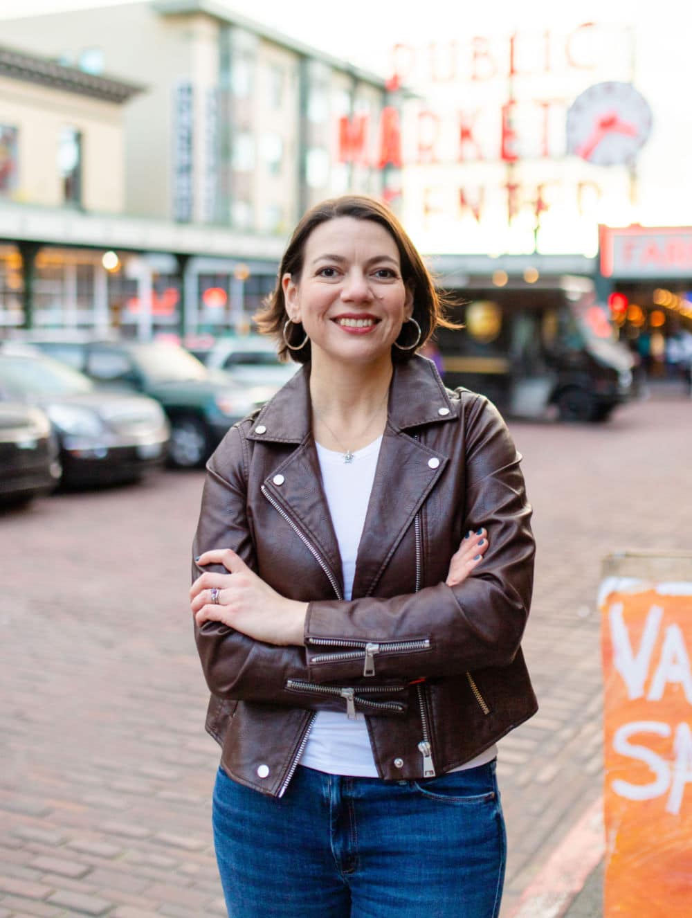 Laura Jawad, Seattle SEO strategist and mentor, standing with arms crossed and smiling in front of Pike Place Market.
